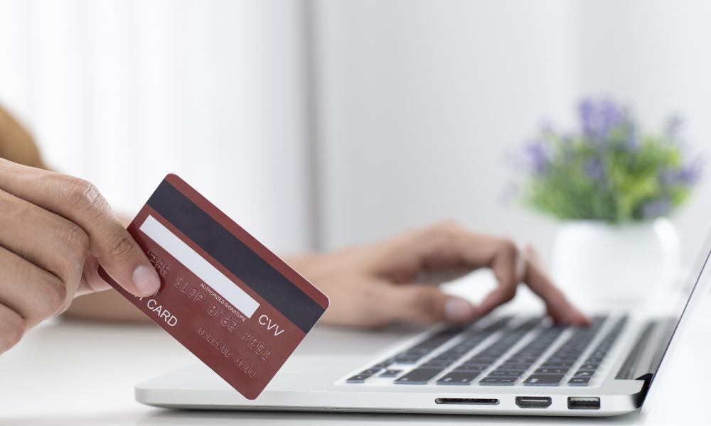 person holding a credit card in front of a laptop